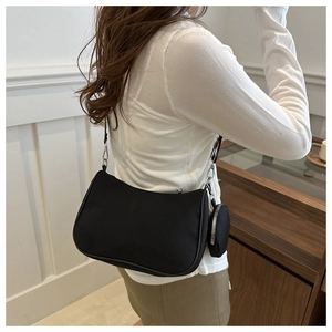 Détail du sac à bandoulière en toile noire avec boucles argentées et mini pochette
