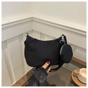 Détail d'un sac à bandoulière en nylon noir avec une petite pochette ronde attachée à la sangle