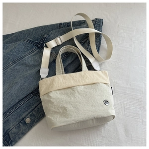 Top view of cream white nylon bucket bag featuring a micro-wrinkle texture and fabric strap