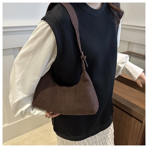 Détail du sac hobo en daim marron foncé sur modèle avec bandoulière réglable et fini rétro