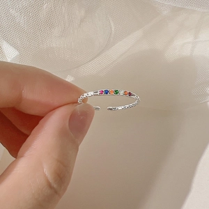 Macro detail of silver irregular open ring with a row of rainbow colored gemstones