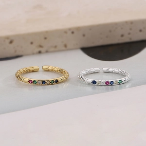 Detail of gold and silver S925 rings with colorful inlaid stones and geometric texture
