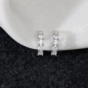 Elegant silver hoop earrings with classic claw-set crystals on white silk background