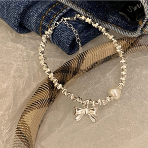 Close-up of S925 silver beaded bracelet with bow pendant and heart-shaped pearl detail