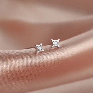 Minimalist S925 silver star stud earrings with zircon on elegant champagne silk background