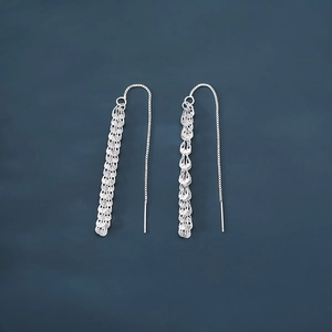 Détail macro de boucles d'oreilles pompons en argent S925 avec franges métalliques