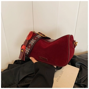 Detail of burgundy velvet pillow bag featuring a retro patterned wide shoulder strap