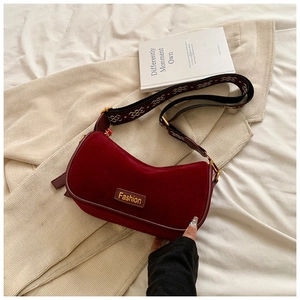 Detail of red suede crescent bag with fashion label and ethnic jacquard strap