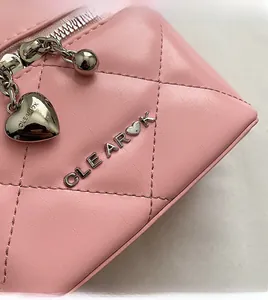 Dettaglio borsa a secchiello in pelle rosa trapuntata con logo e ciondolo a cuore