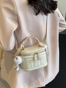 Chic cream white box bag with silk scarf handle and plush charm on a model's shoulder