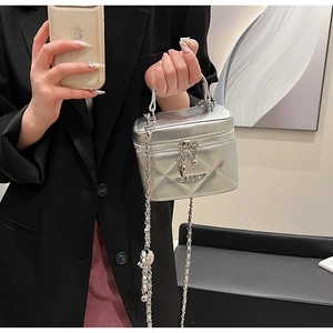 Detail of silver quilted chain bag with metallic handle and dual zipper closure
