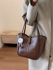 Brown leather tote bag with vertical stitching and plush charm for women commute