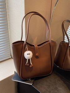 Minimalist coffee brown tote bag in matte faux leather with a cute plush monster charm