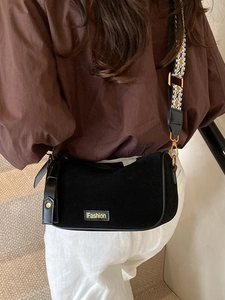 Retro black suede pillow bag with jacquard shoulder strap worn as a crossbody bag