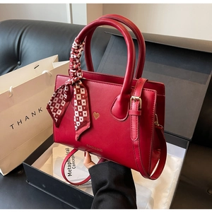 Detailansicht der roten Ledertasche mit Seidenschal und Herzstickerei in einer Geschenkbox