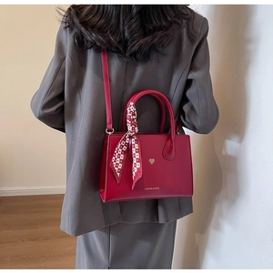 Rote Tragetasche mit Seidenschal und Herzlogo zu einem grauen Blazer-Outfit