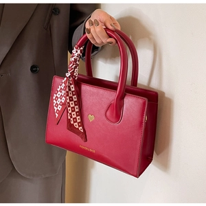 Detail der roten matten Ledertasche mit goldenem Herz und Seidentuch am Griff