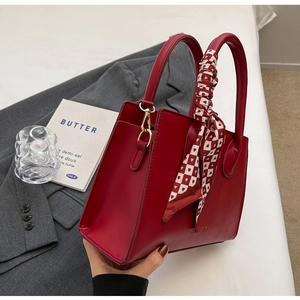 Detailansicht der roten Ledertasche mit Seidenschal-Griff und goldenen Beschlägen