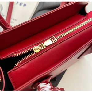 Detailaufnahme der roten Leder-Tasche mit goldenem Reißverschluss und Seidenband-Griff