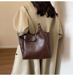 Detail of dark coffee tote bag with diamond quilted texture and gold chain strap