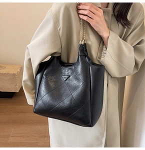 Close-up of black quilted PU leather tote bag with iconic metal triangle logo detail