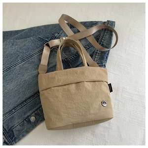 Detail of khaki nylon kids crossbody bag with metal logo on denim jacket