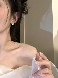 Gros plan de boucles d'oreilles fleur en perles sur un mannequin avec base dorée