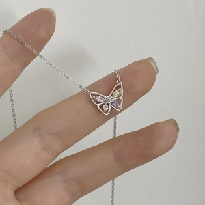 Macro detail of butterfly pendant with colorful zircon stones on silver chain necklace