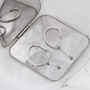 Minimalist silver chain earrings with textured hoops in a mirrored jewelry box
