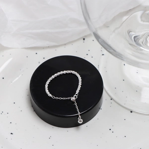 Macro detail of adjustable silver chain ring with textured beads and pull-string closure