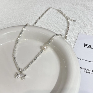 Elegant 925 silver bow pendant necklace with pearls on a minimalist white tray backdrop