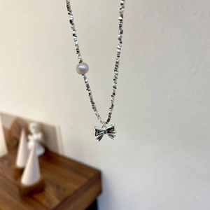 Macro view of bow pendant and silver beads on a freshwater pearl necklace