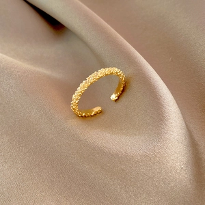 Bague dorée minimaliste ajustable avec texture irrégulière sur tissu en soie champagne
