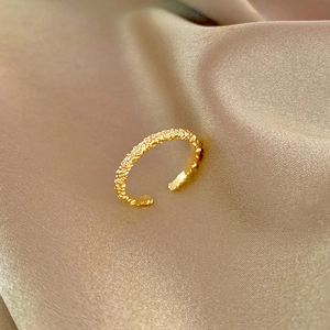 Bague ajustable dorée de style français à texture irrégulière sur fond de soie élégant