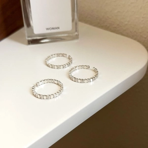 Three adjustable S925 sterling silver rings with cubic zirconia inlay on white stand