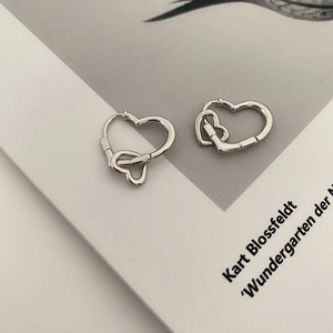 Boucles d'oreilles double cœur en argent poli sur des pages de livres artistiques