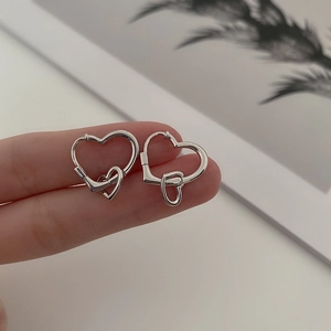 Détail des boucles d'oreilles double cœur argentées montrant le mécanisme de fermeture
