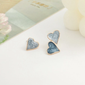 Macro shot of asymmetric heart earrings with blue marble enamel in gold settings