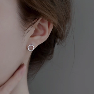 Macro view of a 925 silver round zircon wreath stud earring worn on a model's ear