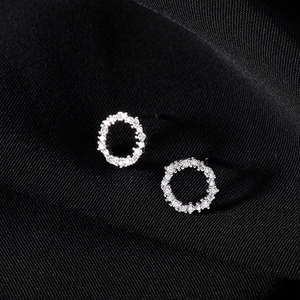 Macro shot of 925 sterling silver hoop earrings with cubic zirconia on black silk fabric