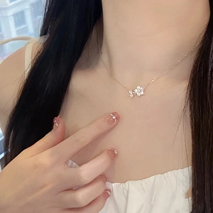 Détail d'un collier en or rose avec pendentif double fleur en nacre blanche et cristaux