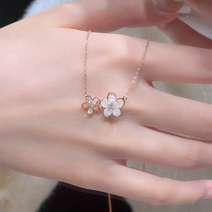 Détail du collier fleur de cerisier or rose avec pétales blancs et pierres micro-incrustées