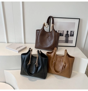 Three large quilted tote bags in brown, black and camel with metal chain straps