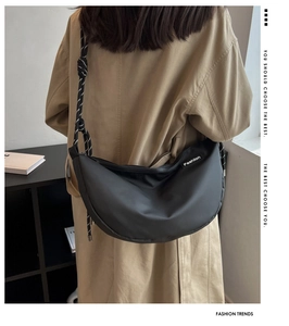 Black crescent crossbody bag featuring textured rope strap and minimalist side label