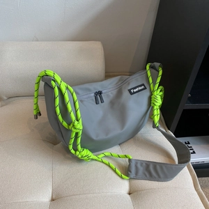 Detail of grey crossbody dumpling bag with neon green woven rope strap and fashion label