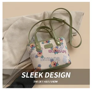 Détail du sac cabas crème avec imprimé dessin animé et lanières vertes contrastées