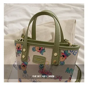 Détail d'une poignée en cuir vert avec rivets dorés sur un sac à motif souris