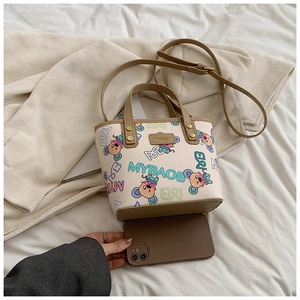 Mini sac cabas avec imprimés de dessins animés et poignées en cuir à côté d'un téléphone