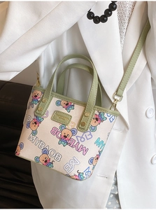 Détail du mini sac cabas imprimé avec poignées vertes et plaque de marque en cuir mode