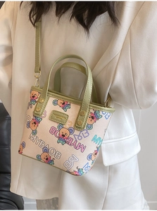 Détail des finitions vert avocat et imprimé dessin animé sur le mini sac crème